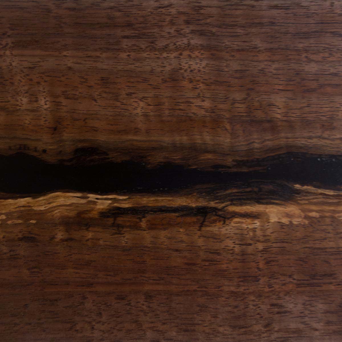 Detailed close up of live edge walnut wood with tiger stripe curl figure and a black epoxy resin river