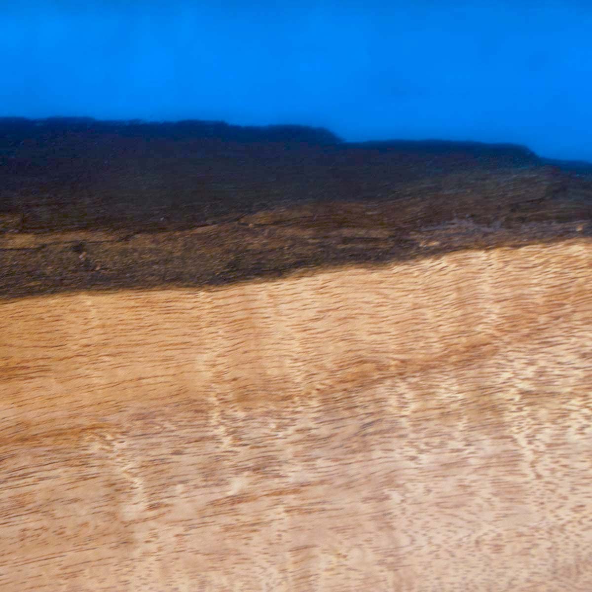 Light tan sweet acacia wood with a light blue epoxy live edge, a detailed up close photo to show the wood grain and live edge detail