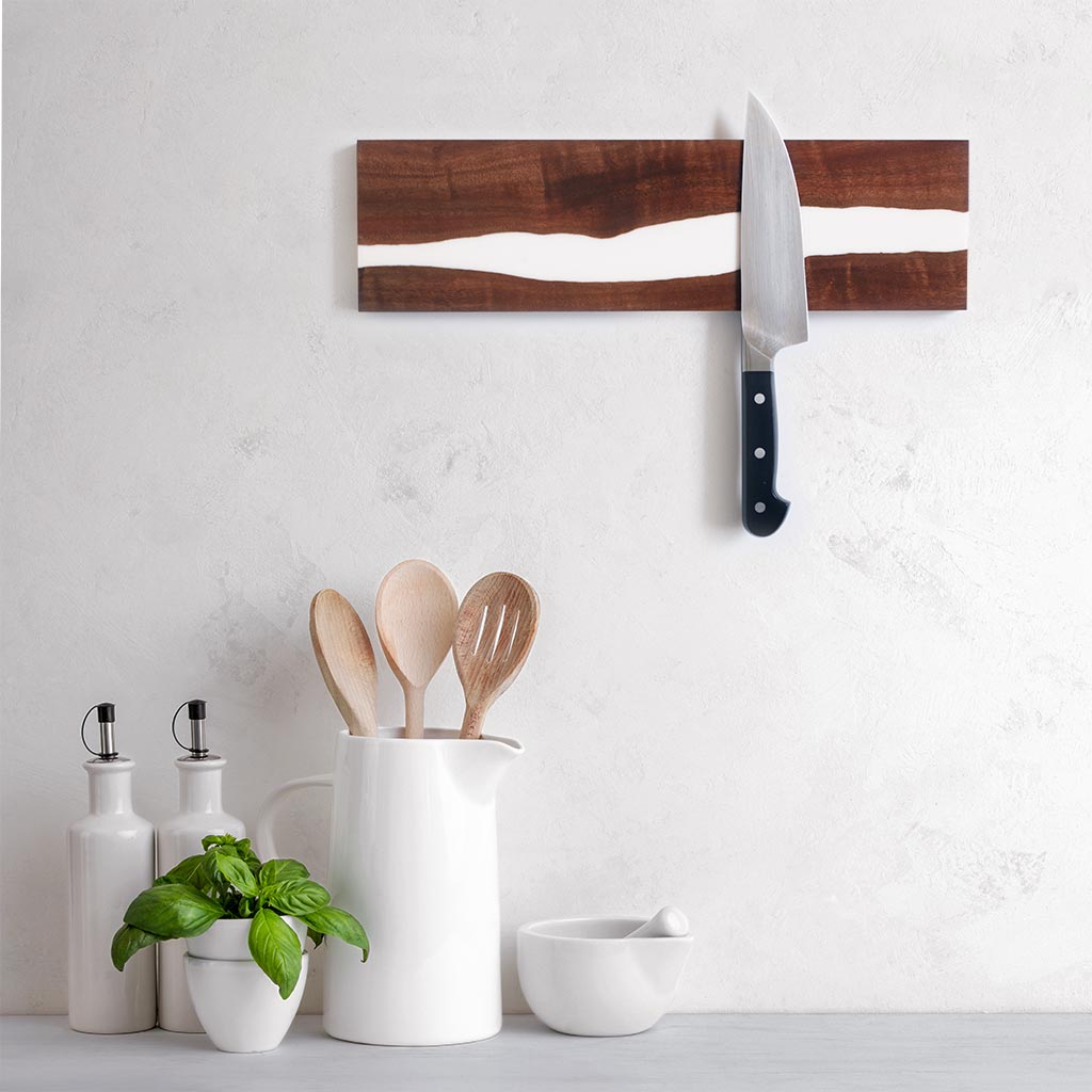 live edge epoxy resin river magentic knife strip holding a chefs knife in a stylish designer white and gray kitchen