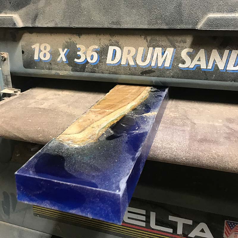 using a drum sander to sand a blue epoxy resin and acacia wood magnetic knife holder