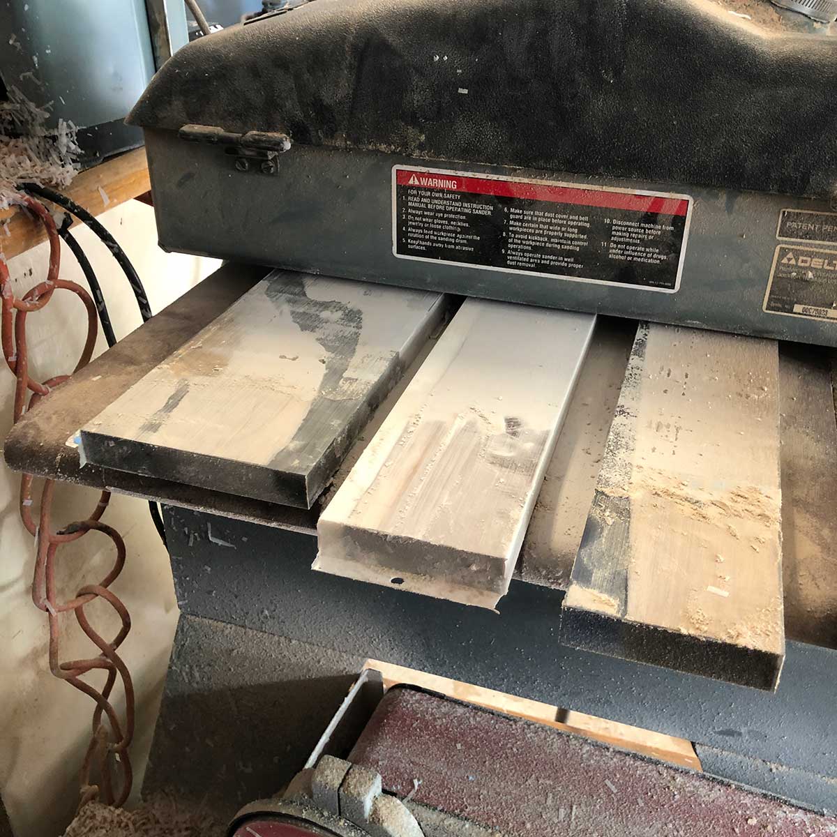 using a drum sander to sand and flatten a batch of wood and epoxy magnetic knife strips