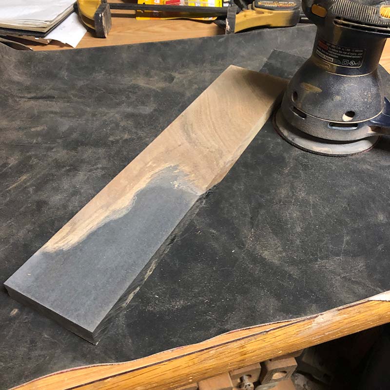 using an orbital sander to hand sand an acacia wood and live edge epoxy resin magnetic knife holder