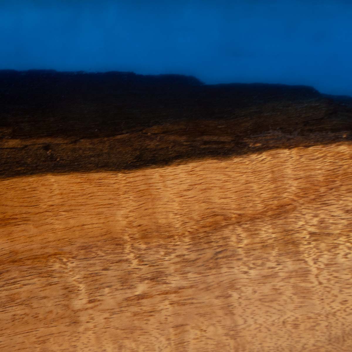 detailed closeup of acacia wood live edge and translucent blue epoxy resin