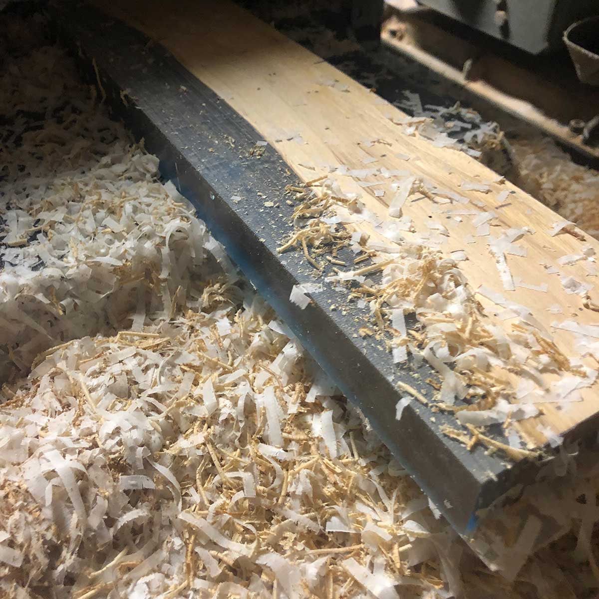 planer shavings and wood chips resting on a workbench after planing a live edge epoxy resin magnetic knife holder