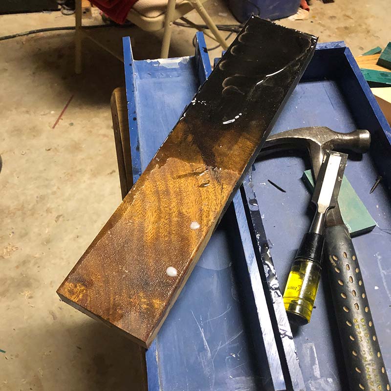 live edge acacia and black epoxy resin knife holder being removed from a plastic epoxy resin form after the resin has cured