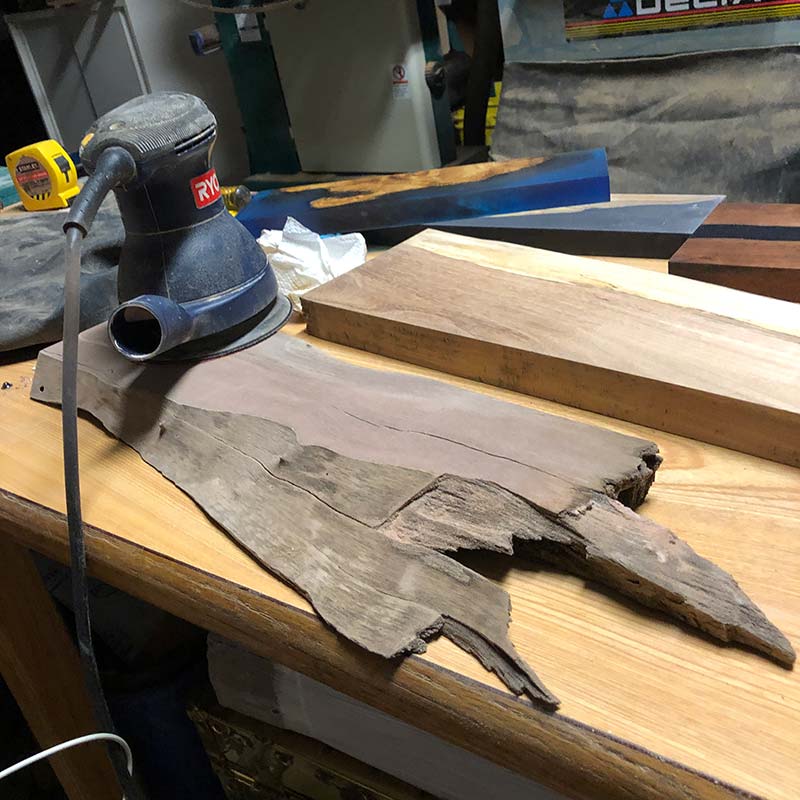 using a plam sander to sand a magnetic knife holder made from live edge hardwood salvaged in south florida